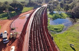 Maquinaria pesada en camino de tierra rodeado de vegetación densa en un ambiente soleado.