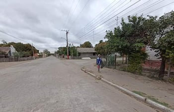 Persona vestida con camiseta azul y pantalones cortos camina por una calle tranquila con casas y árboles en ambos lados.