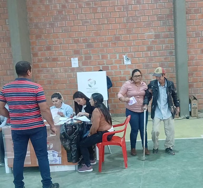Hombre mayor con bastón recibe ayuda de mujer durante los comicios electorales
