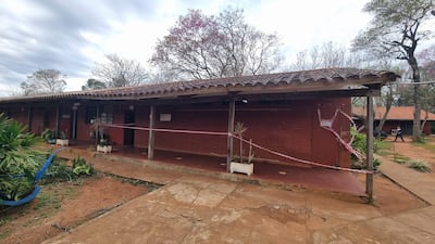 Entorno desértico del Colegio Nacional Rigoberto Caballero, con vegetación y cinta de precaución por riesgo.
