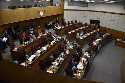 Dionisio Oswaldo Amarilla Guirland en traje oscuro, con expresión tranquila, rodeado de asistentes en un ambiente legislativo moderno.