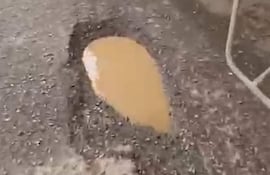 Charco de agua marrón sobre camino de tierra en zona rural tras lluvias recientes.