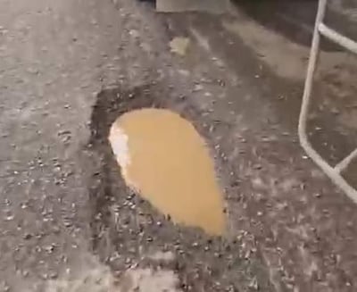 Charco de agua marrón sobre camino de tierra en zona rural tras lluvias recientes.