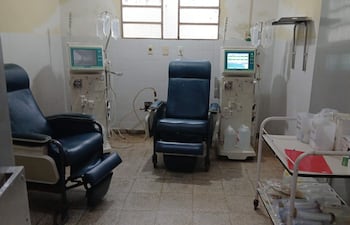 Sillones de hemodiálisis en un hospital, con máquinas y suministros médicos visibles en un ambiente desgastado.
