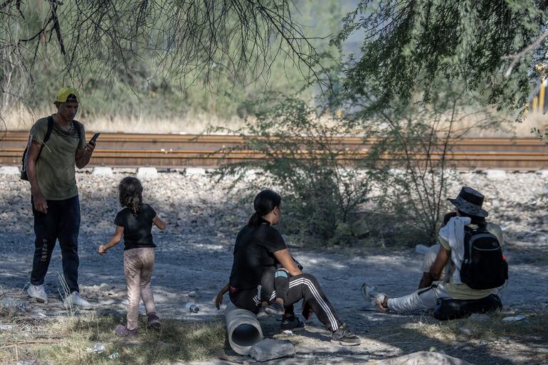 Migrantes descansan al costado de las vías del tren en su intención de llegar a la frontera con Estados Unidos hoy, en el municipio de Escobedo (México). 