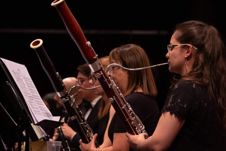 Dos fagotistas con gafas y cabello recogido, en el escenario, vestidos de negro y concentrados en su ejecución.