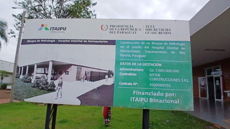 Cartel informativo de construcción de bloque de nefrología, con ambulancia visible y vegetación alrededor.
