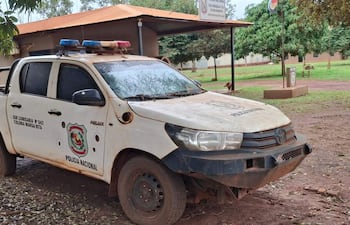 Camioneta Toyota Hilux de la Policía Nacional, en estado de desgaste, estacionada en un área verde sin agentes visibles.