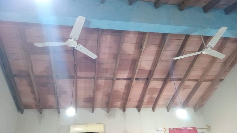 Interior de una habitación con techos de madera, ventiladores y luces encendidas. No hay personas presentes.