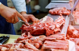 Un carnicero corta carne en una carnicería.