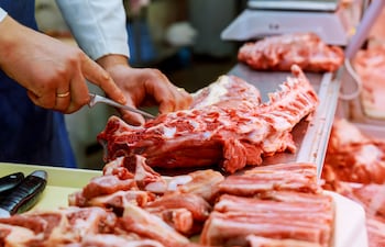 Un carnicero corta carne en una carnicería.