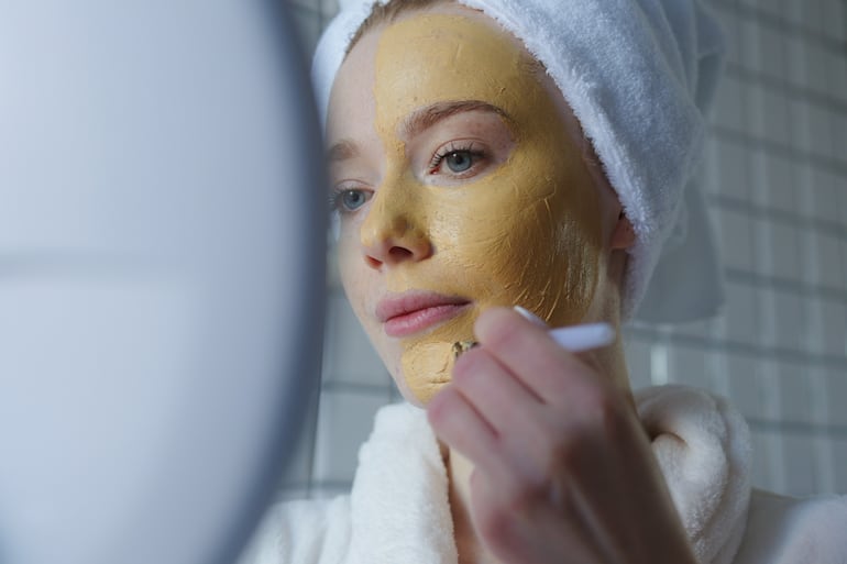 Mujer se aplica una mascarrilla de productos con cúrcuma.