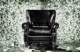 Un sillón de cuero negro rodeado de billetes de dólares.