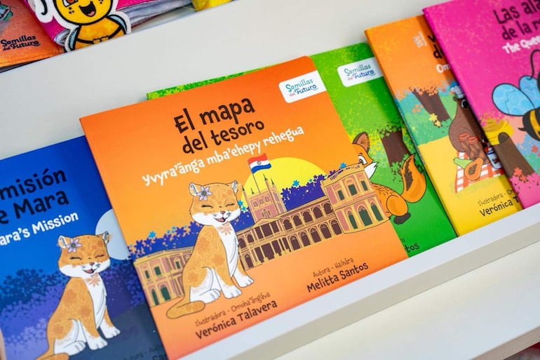 Estantería con libros infantiles coloridos de autores paraguayos, incluyendo 'El mapa del tesoro' y 'Las alegrías de la lluvia'.