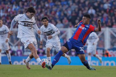 Ezequiel Herrera y Vicente Taborda disputan el balón. Ronaldo Martínez observa el desenlace de la acción.