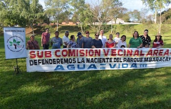 Vecinos en el parque Mbaracayú frente a pancarta que dice 'Defenderemos la naciente del Parque Mbaracayú'.