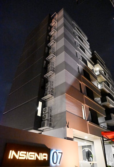 Edificio de fachada moderna iluminado en la noche, destacando sus ventanas y unidades de aire acondicionado.
