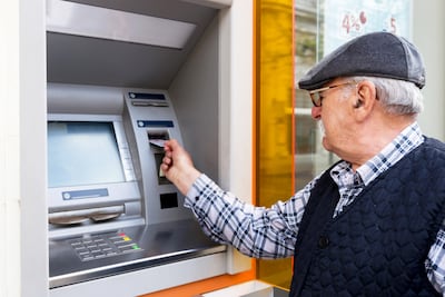 Un hombre de la tercera edad extrae dinero de un cajero automático.