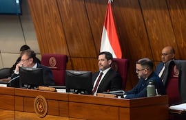 Raúl Latorre Martínez sentado en escritorio con corbata, visibly tranquilo durante una sesión en recinto legislativo.
