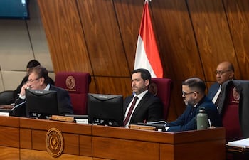 Raúl Latorre Martínez sentado en escritorio con corbata, visibly tranquilo durante una sesión en recinto legislativo.