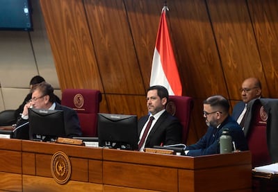 Raúl Latorre Martínez sentado en escritorio con corbata, visibly tranquilo durante una sesión en recinto legislativo.