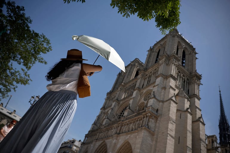 Una persona se protege del sol bajo un paraguas frente a la catedral de Notre-Dame en París, mientras una ola de calor temprana y récord azota amplias zonas de Europa occidental el 28 de mayo de 2026.