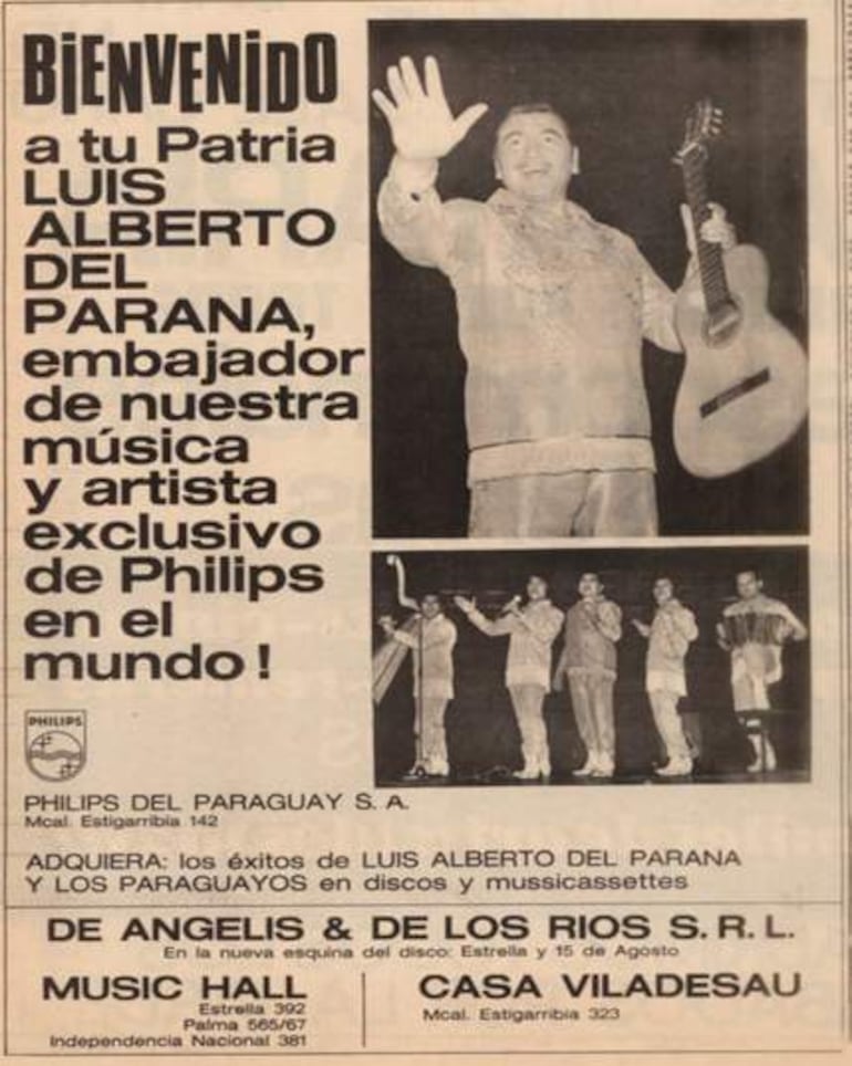 Luis Alberto del Paraná sostiene una guitarra, expresando felicidad mientras interactúa con el público en un cartel de bienvenida.