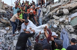 Voluntarios y rescatistas mueven un cuerpo sacado de entre los escombros del edificio colapsado.