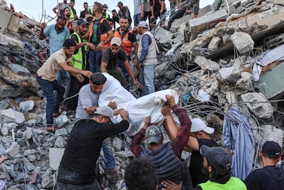 Voluntarios y rescatistas mueven un cuerpo sacado de entre los escombros del edificio colapsado.