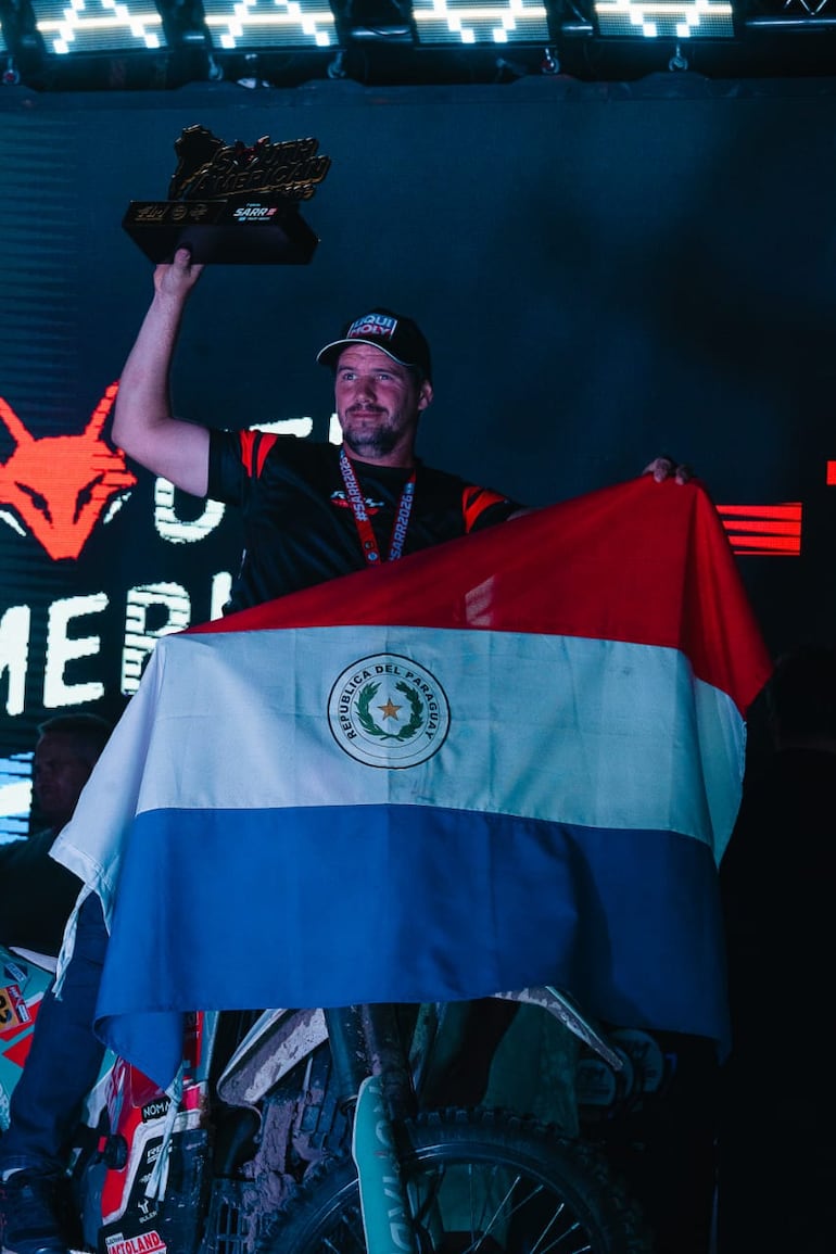 La bandera tricolor en el podio junto a Gido Krahn y su trofeo.