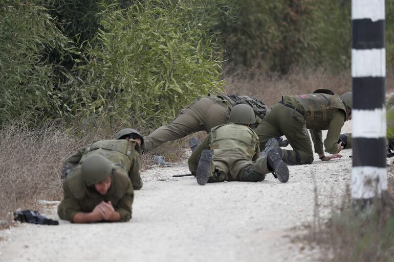 Soldados israelíes se cubren durante el ataque de un misil cerca de la frontera con Gaza, cerca de Sderot, al sur de Israel.