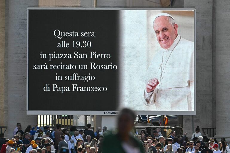 na pantalla gigante que representa al difunto Papa Francisco y la lectura "Esta tarde a las 7:30 p.m. en la Plaza de San Pedro, se rezará un Rosario en sufragio del Papa Francisco" en la plaza de San Pedro, después de su muerte, en el Vaticano el 21 de abril de 2025. La primera oración pública por el Papa Francisco después de su muerte tendrá lugar en la Plaza de San Pedro.