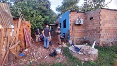 Grupo de cinco personas en un área de ladrillo. Un joven con camiseta negra supervisa a otros en un ambiente de trabajo.