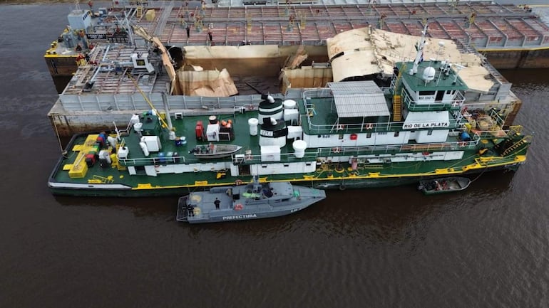 Barco de carga 'Río de la Plata' atracado, sin personas visibles, en un entorno acuático con embarcación de la Prefectura Naval cerca.