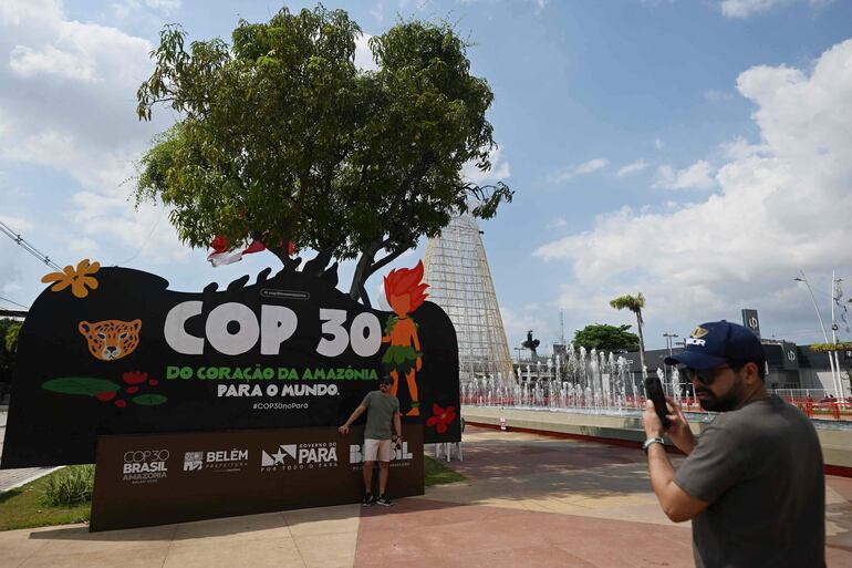Un turista se fotografía con una pancarta de la COP30 que muestra a su mascota, Curupira, en Belém, estado de Pará, Brasil.