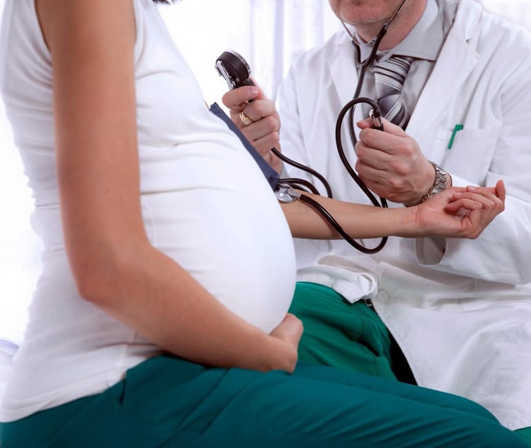 Un médico realiza un control prenatal a una embarazada. 