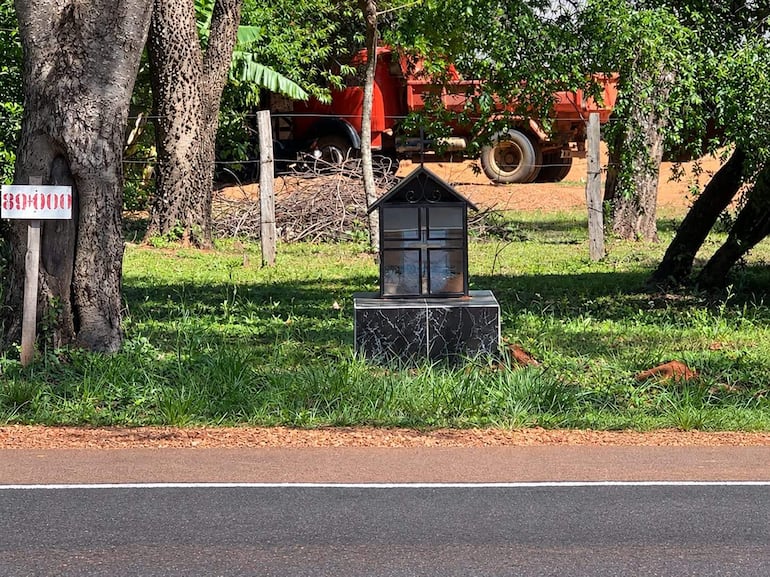 Construcción de forma de capilla en área verde con una maquinaria agrícola roja al fondo.