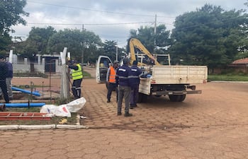 Tres hombres, uno con chaleco amarillo y otro con abrigo azul, supervisan trabajos con herramientas de construcción en un entorno urbano.