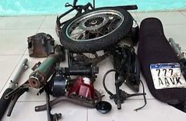 Piezas de motocicleta desarmada en taller, con matrícula '777 AAVK' visible en el ambiente desordenado.