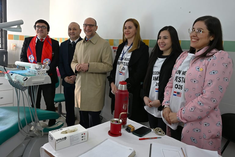 Seis personas sonríen en un consultorio dental, con equipo visible y una mesa presentada en el fondo.