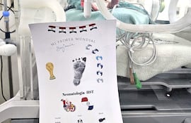 Recién nacido en incubadora con documentos que celebran su primer Mundial, destacando huellas y gráficos relacionados con el fútbol.