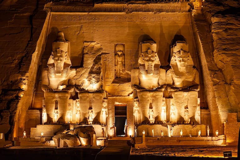 Gran templo de Abu Simbel con colosos de faraones, iluminado suavemente en un entorno desértico.