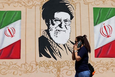 Una mujer camina frente a un mural en Teherán, Irán, que retrata al fallecido ayatolá Alí Jameneí.