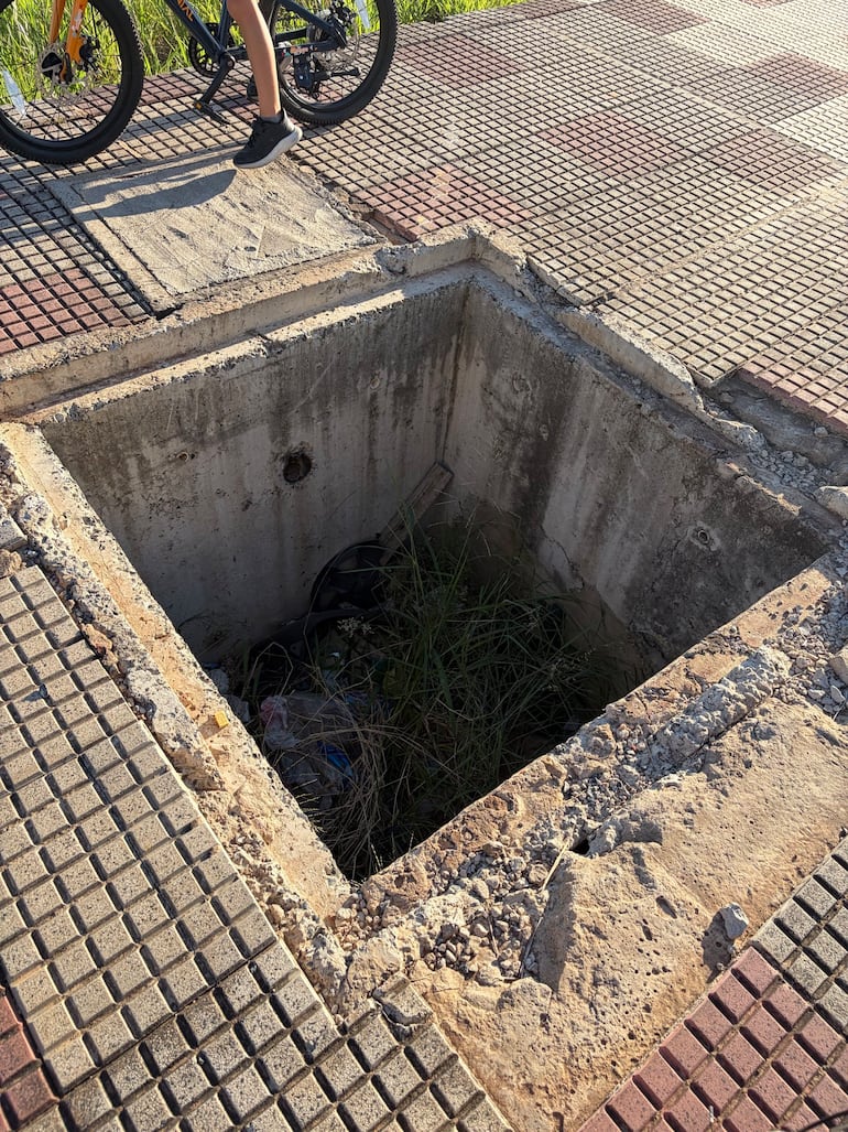 Las fotos muestran la bicicleta del pequeño dentro del pozo cuadrado, con basura y pasto crecido