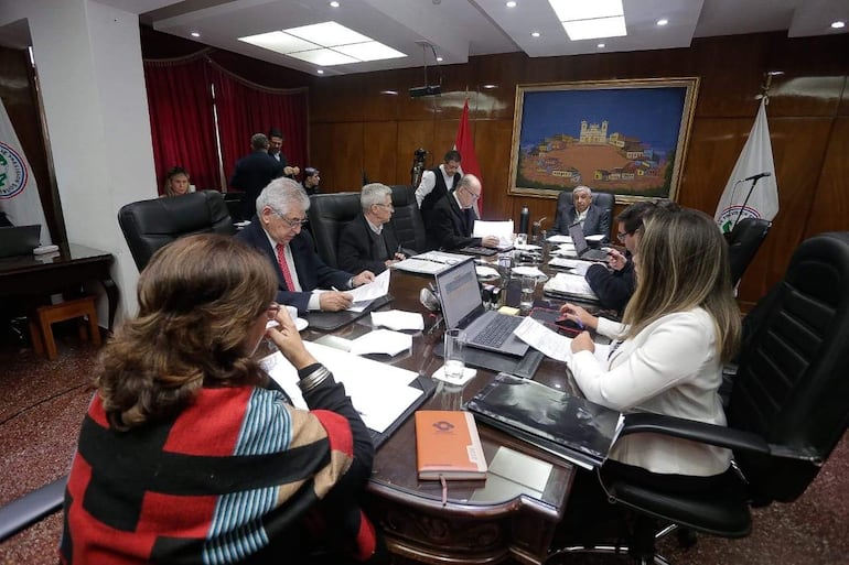 Isaías Ricardo Fretes, José Jara Rojas y otros en reunión, todos con actitud tranquila, revisando documentos en un ambiente serio.