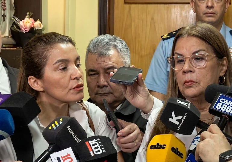 Rossana González, de cabello castaño y lacio, habla al micrófono, acompañada por Shirley Ferreira con gafas, rodeadas de periodistas.