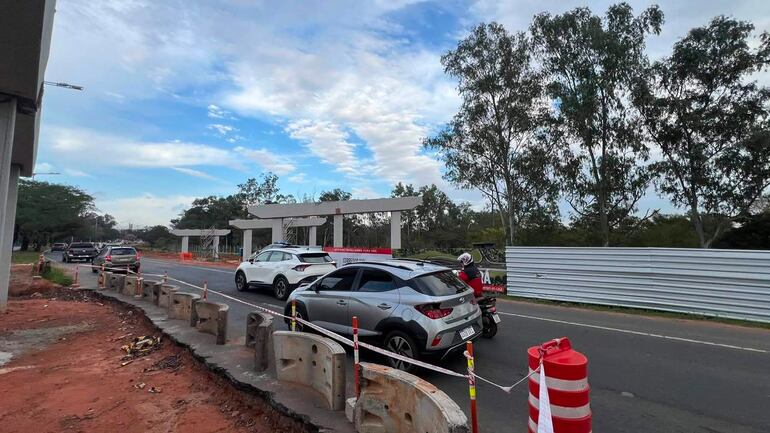 Escena de tráfico con varios coches en movimiento y barreras de obra en avenida en construcción.