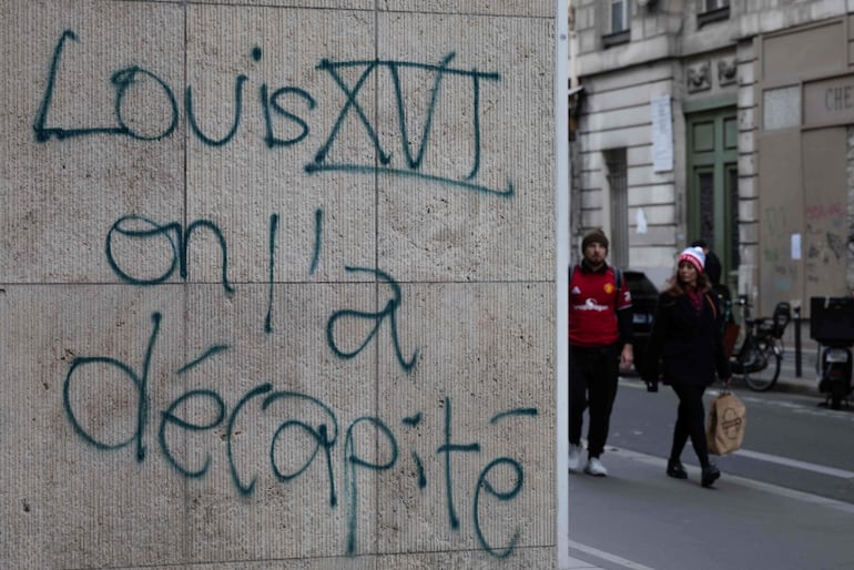 Una pareja pasa junto a una pintada que dice «Luis XVI: le cortamos la cabeza», en el centro de París. El primer ministro de Francia informó que 1.200 personas fueron detenidas durante las protestas registradas en todo el país el 17 de octubre, y que 150 agentes de policía resultaron heridos en los enfrentamientos con los manifestantes.