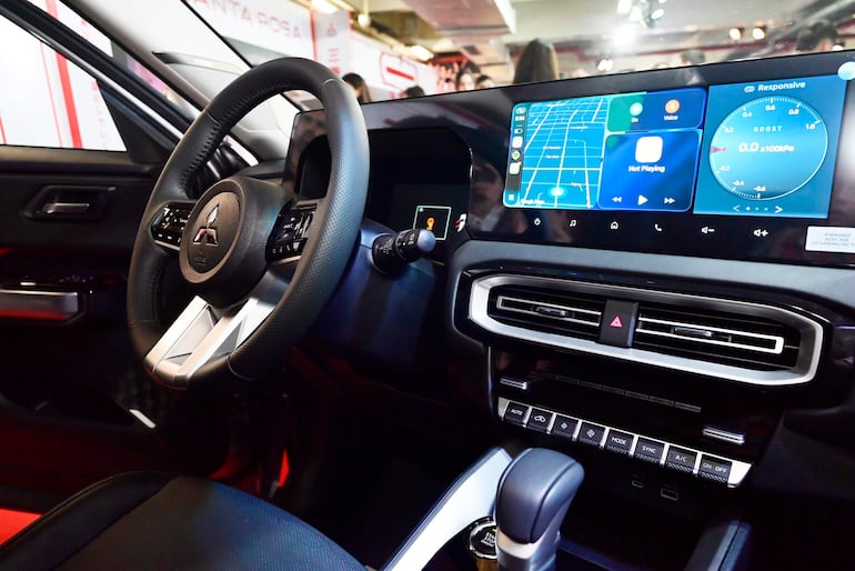 Interior de un automóvil moderno con volante elegante y pantalla digital que muestra navegación y funcionalidades.