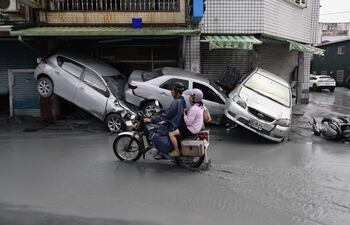 Motociclistas pasan junto a vehículos dañados en una calle inundada tras el paso del supertifón Ragasa en el municipio de Guangfu, condado de Hualien, Taiwán.